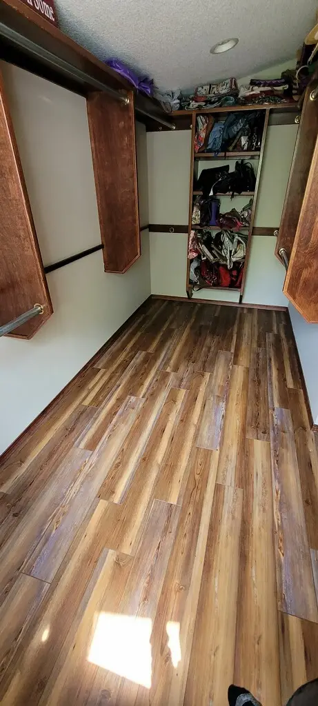 Narrow walk-in closet with open shelves and hanging rods, clothes and bags stored on shelves and in the center closet.